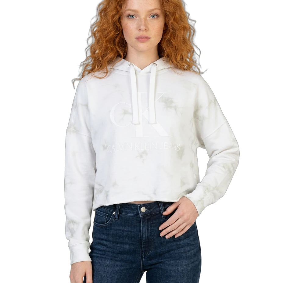 Woman wearing a white tie-dye Calvin Klein hoodie and blue jeans on a white background