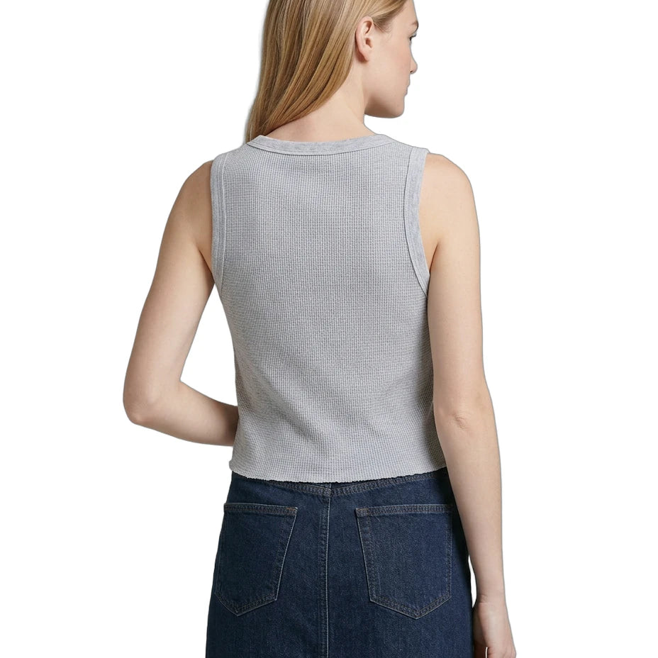 Woman wearing a sleeveless gray Calvin Klein top and dark blue denim skirt on a white background