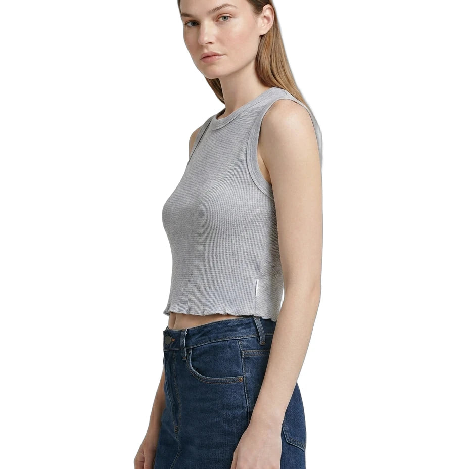 Woman wearing a gray sleeveless Calvin Klein top and blue jeans on a white background