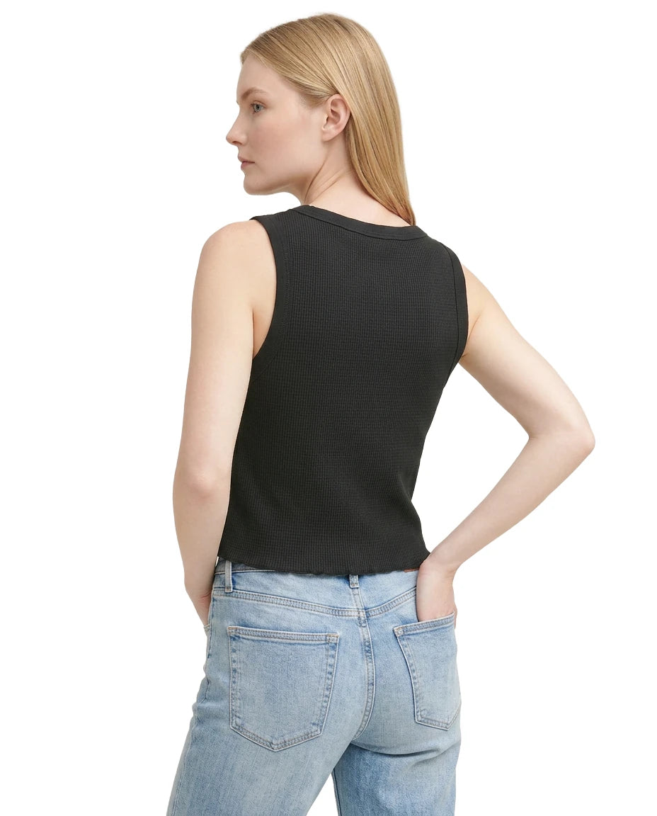 Woman wearing a black sleeveless top and light blue jeans on a white background
