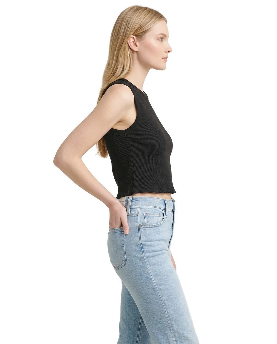 Woman wearing a black sleeveless top and light blue jeans on a white background