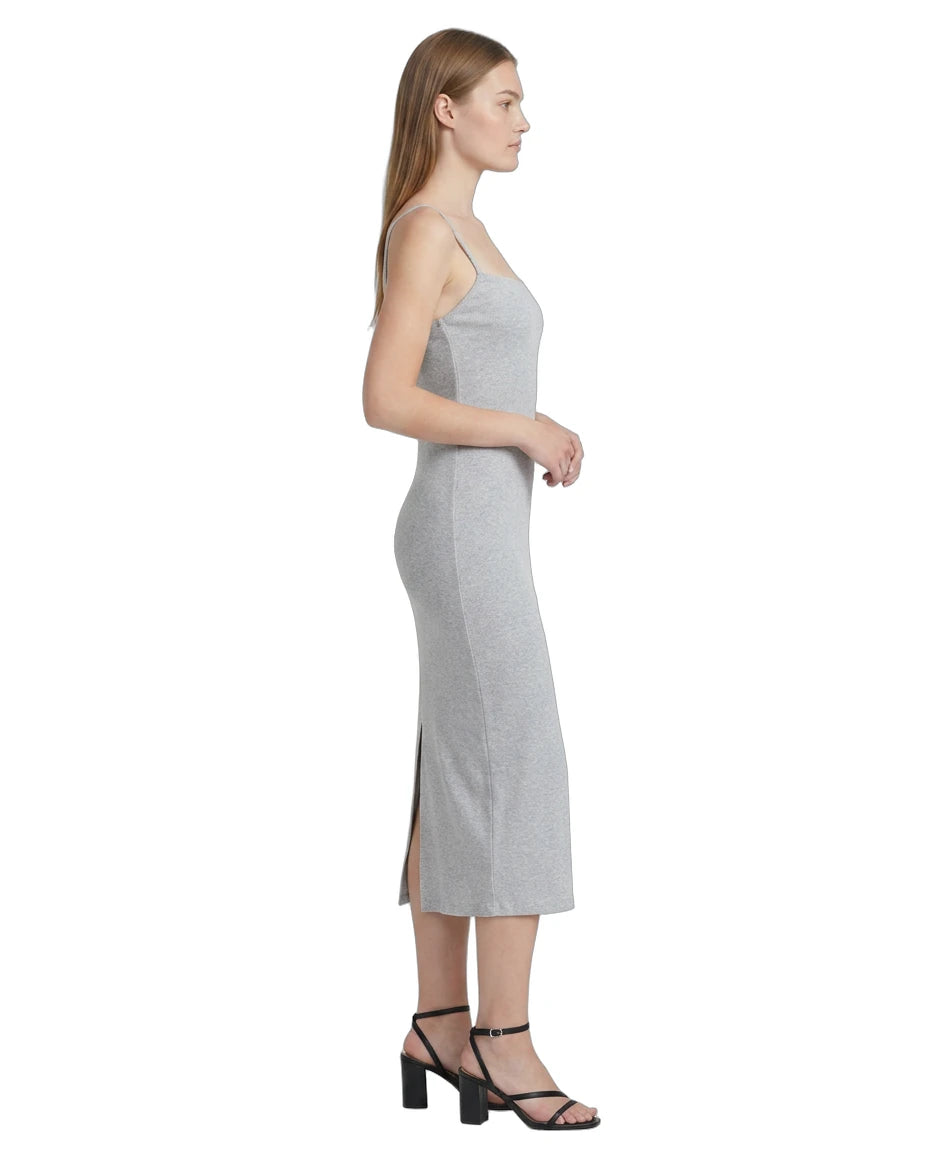 Woman wearing a gray Calvin Klein dress with a side slit on a white background