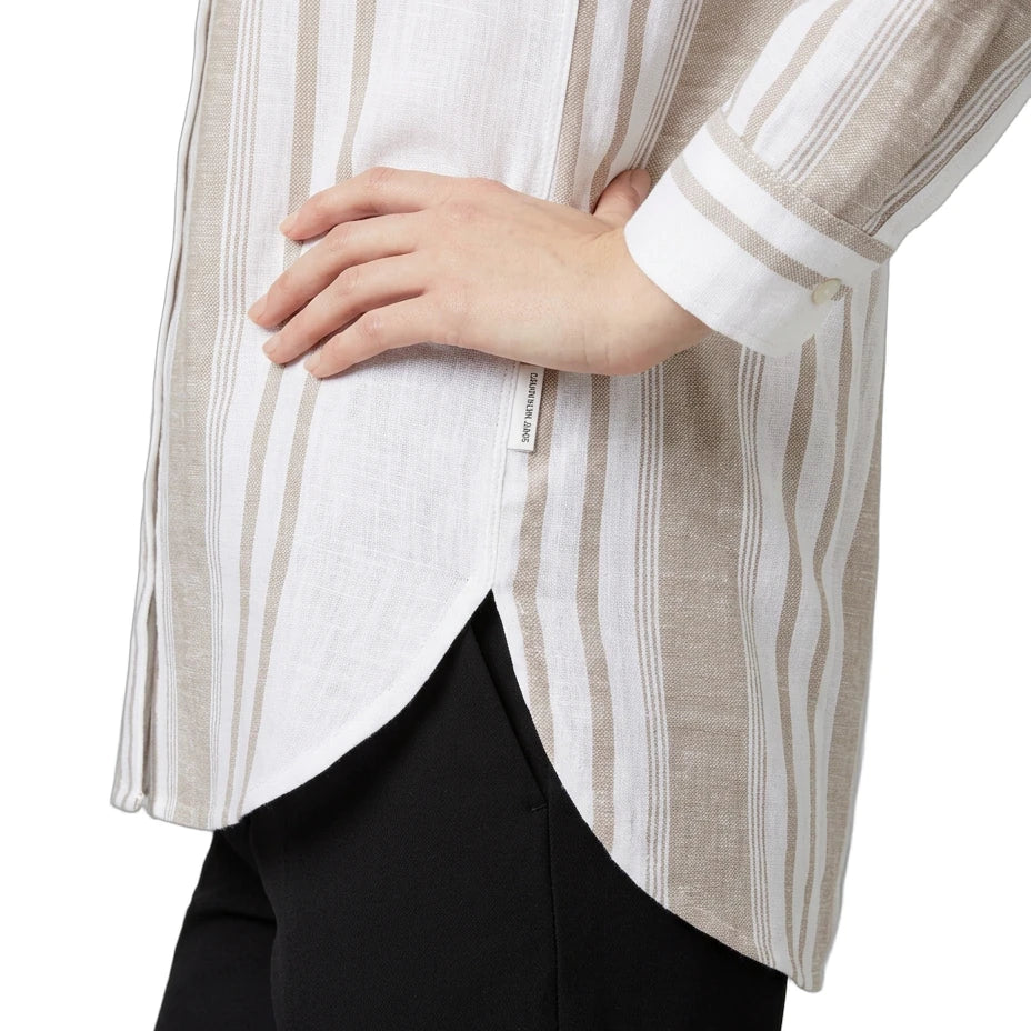 Close-up of a person wearing a striped Calvin Klein shirt with a white background