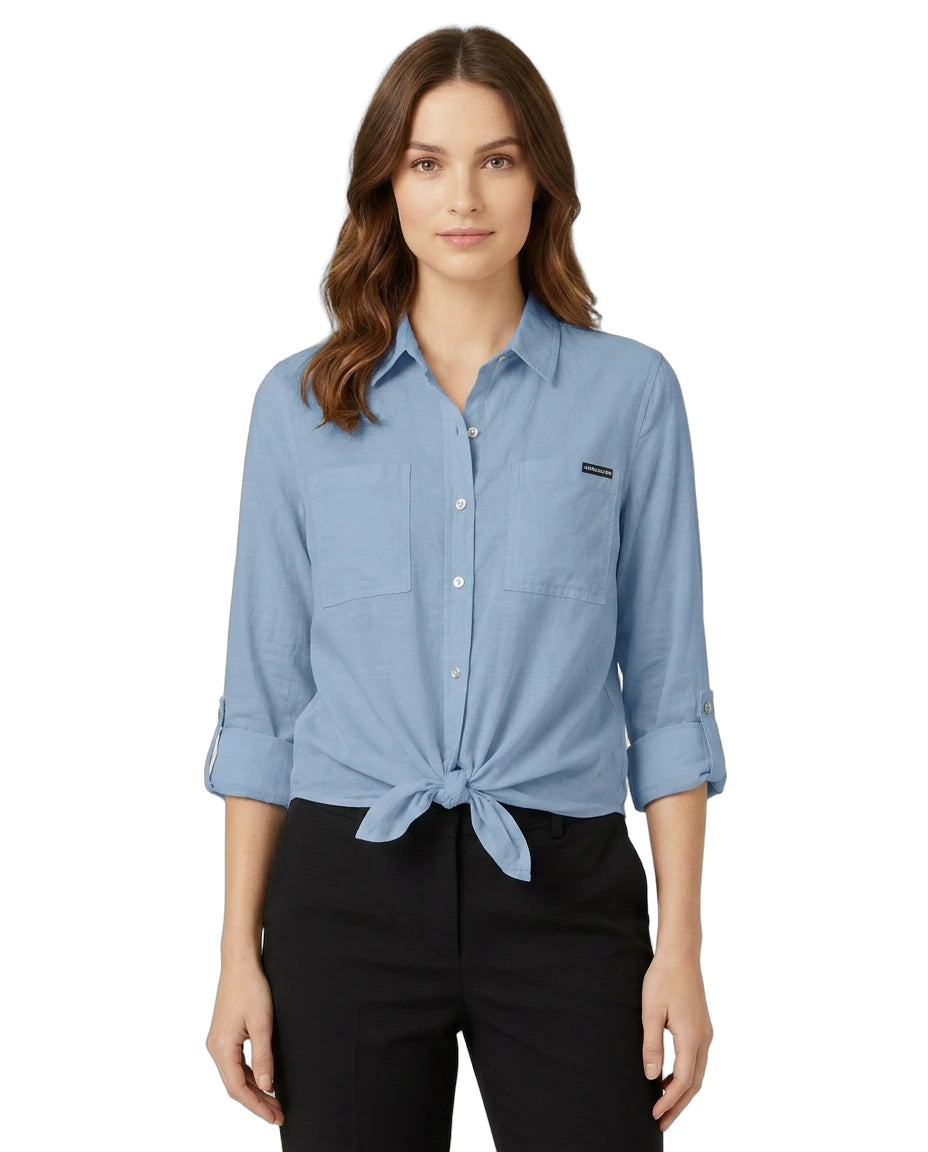 Woman wearing a blue Calvin Klein button-up shirt with a brand logo on a white background
