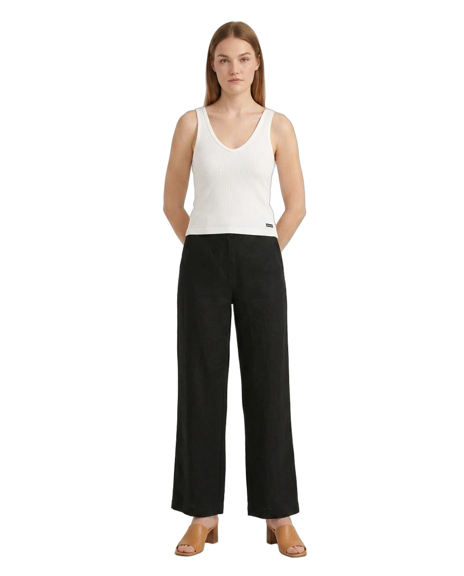 Woman wearing a white sleeveless Calvin Klein top and black wide-leg pants on a white background