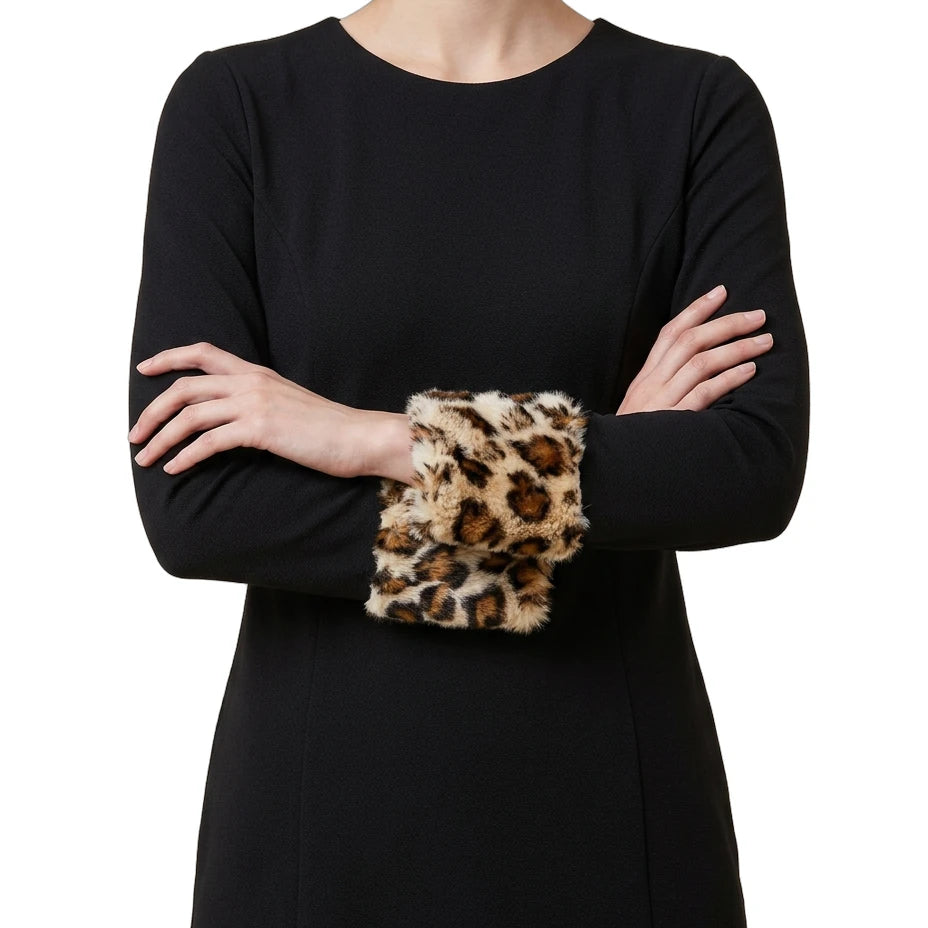 Person wearing a black Calvin Klein dress with leopard print cuffs on a white background
