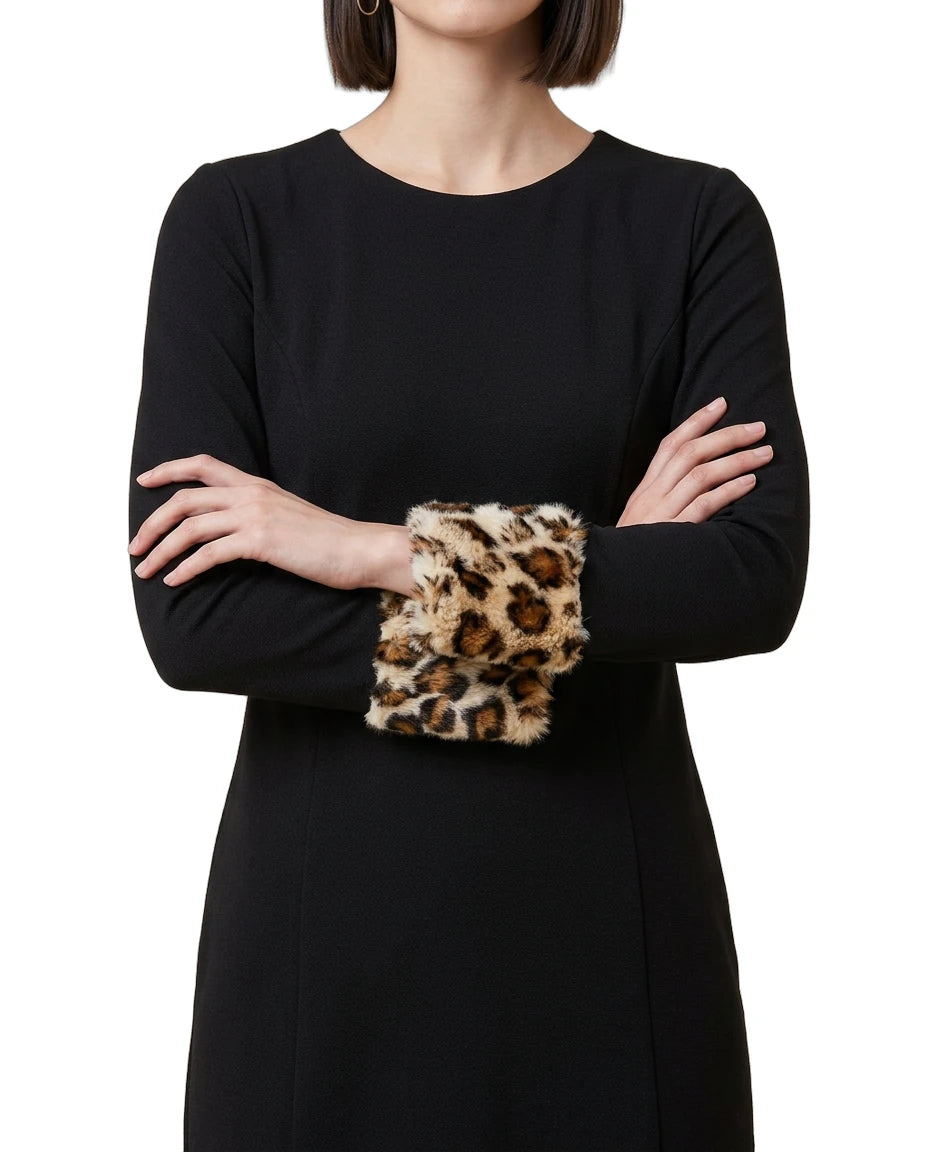 Person wearing a black Calvin Klein dress with leopard print cuffs on a white background