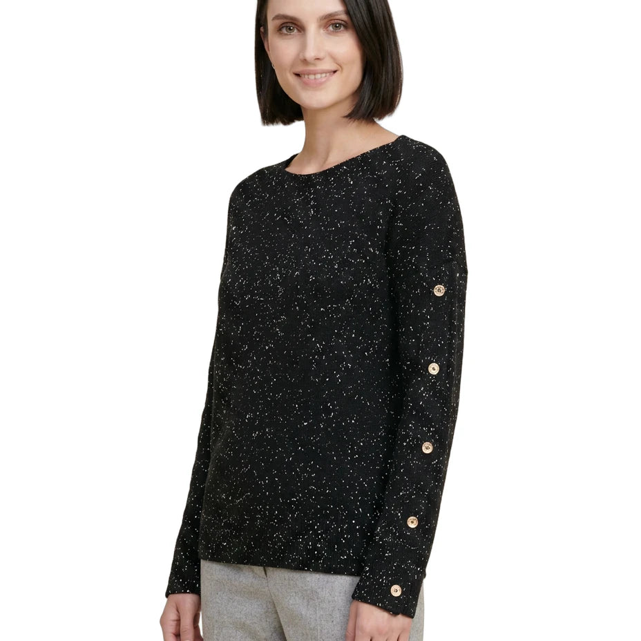 Woman wearing a black speckled sweater with gold buttons on a white background
