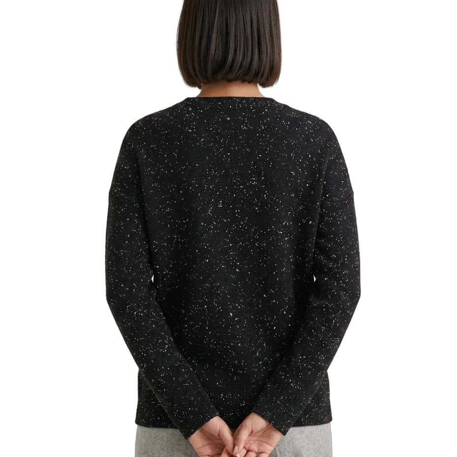 Person wearing a black speckled sweater on a white background