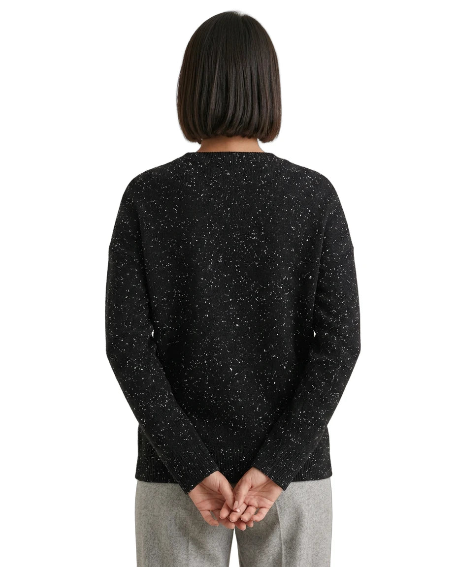 Person wearing a black speckled sweater on a white background