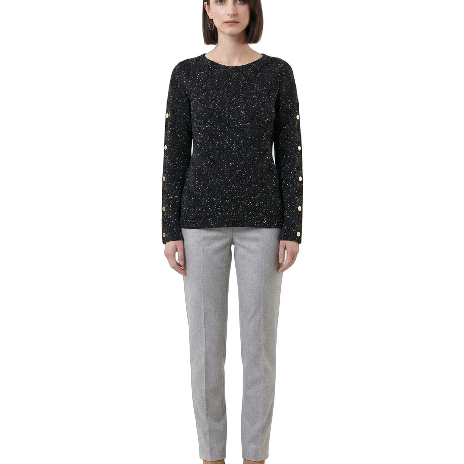 Woman wearing a black sweater with gold buttons and gray pants on a white background