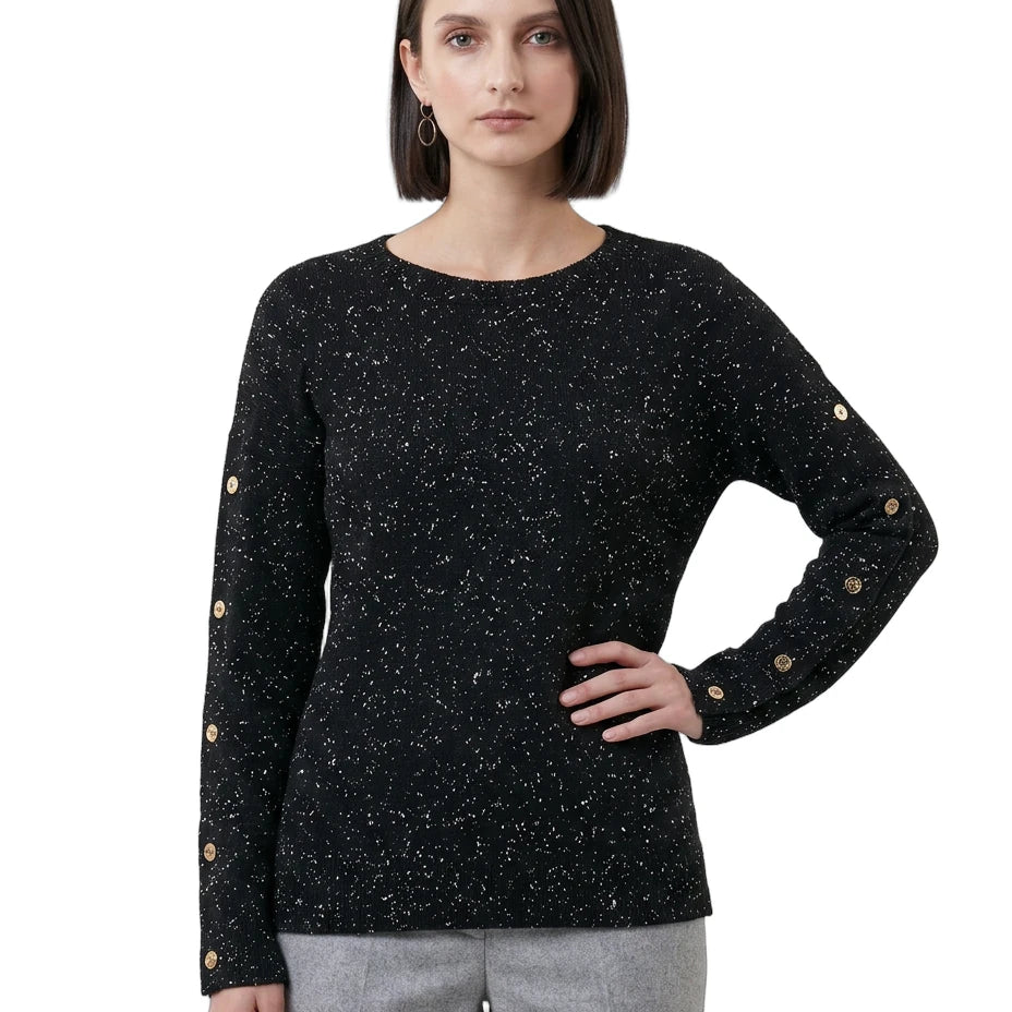 Woman wearing a black speckled sweater with gold buttons on a white background