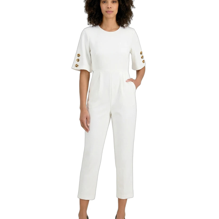 Woman wearing a white jumpsuit with gold buttons on a white background