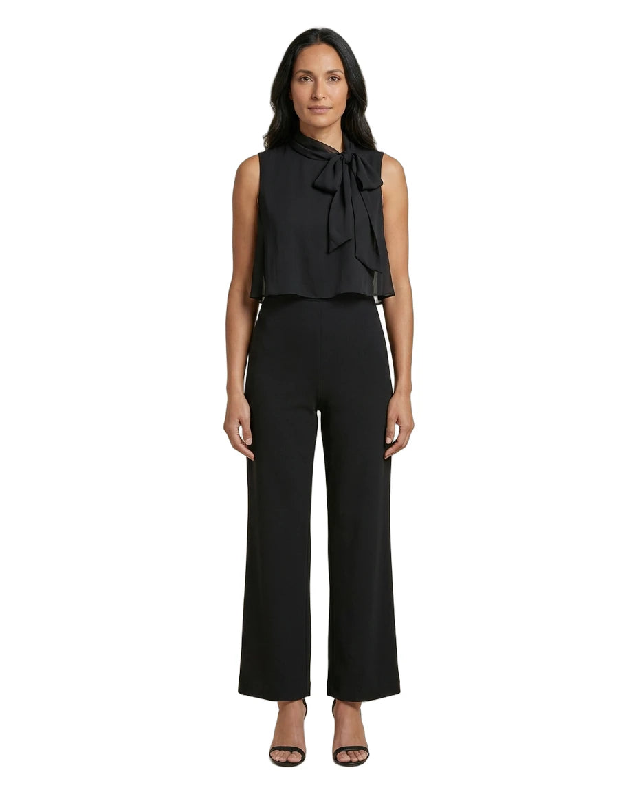 Woman wearing a black sleeveless top with a bow and black pants on a white background