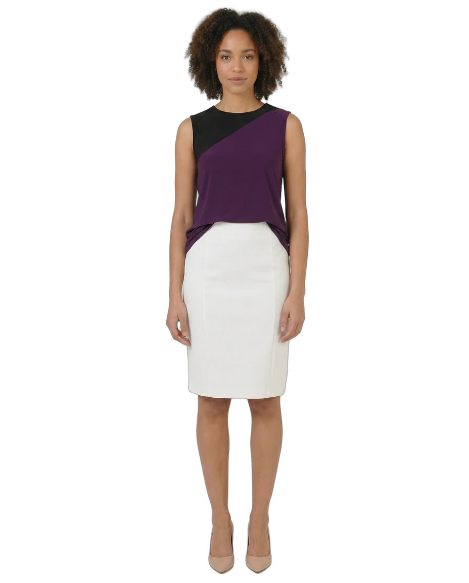 Woman wearing a two-tone dress with a black and purple top and white skirt on a white background