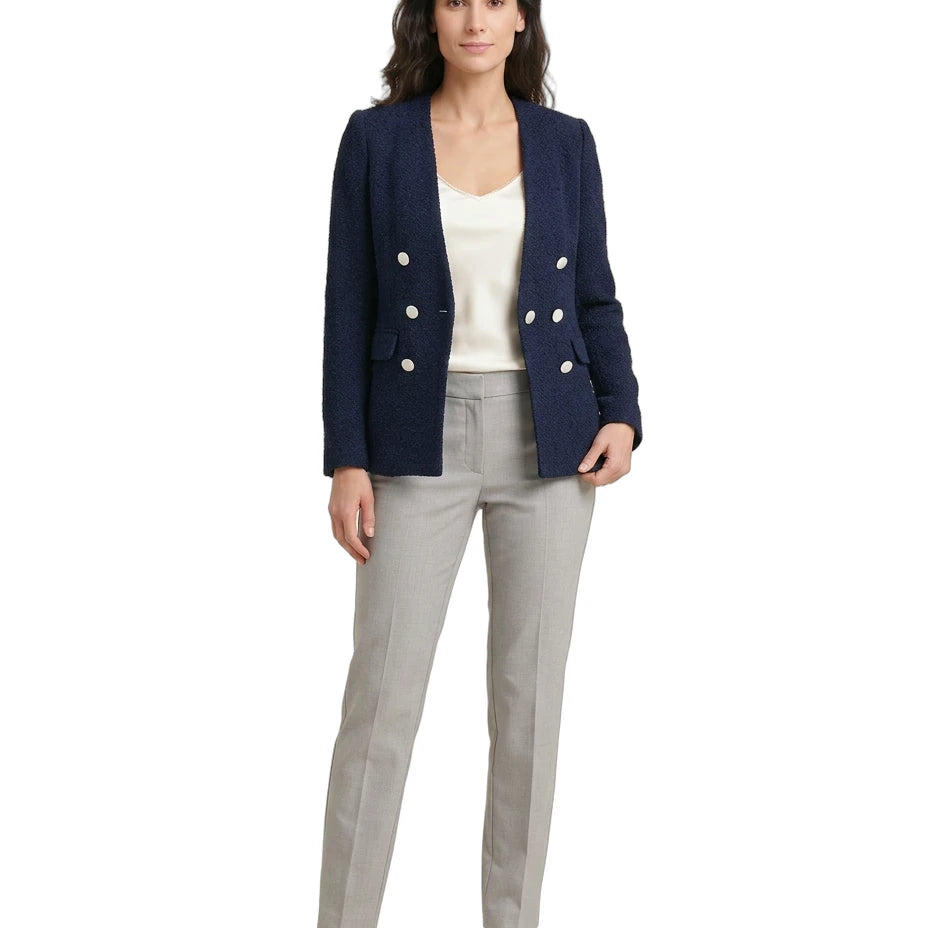 Woman wearing a navy blazer with white buttons, white top, and gray pants on a white background