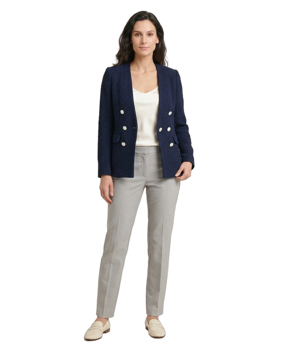 Woman wearing a navy blazer with white buttons, white top, and gray pants on a white background