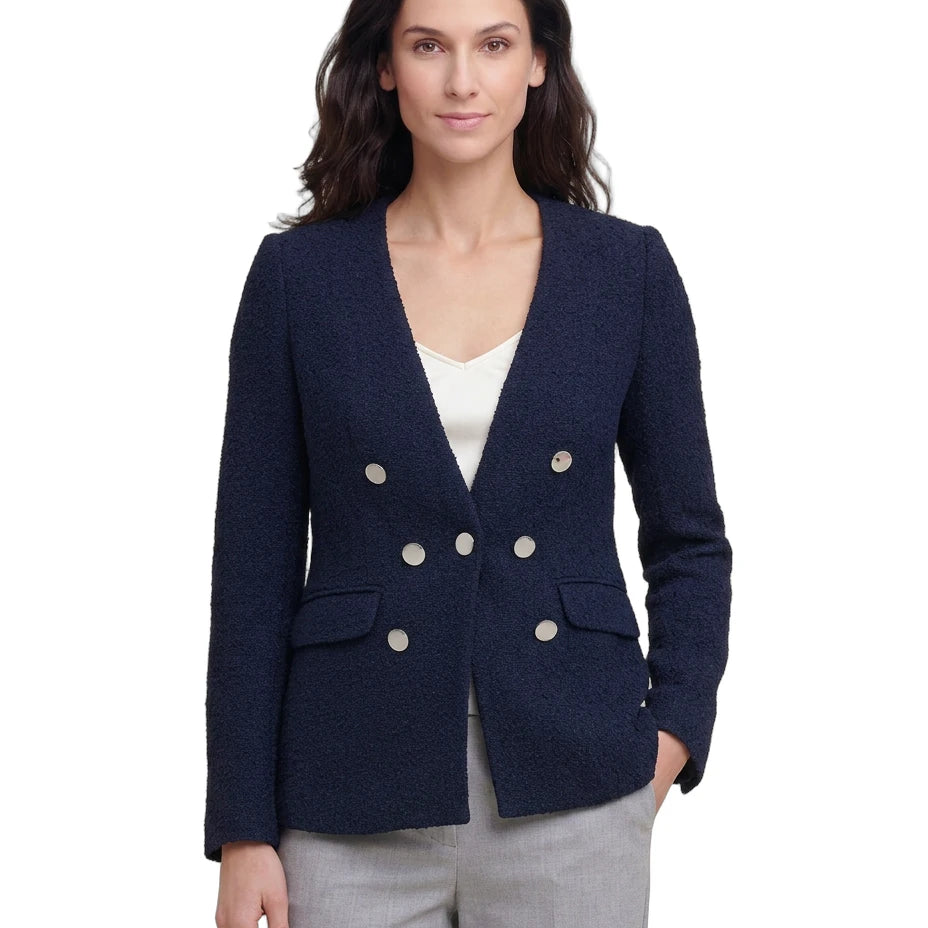 Woman wearing a navy blue blazer with silver buttons on a white background