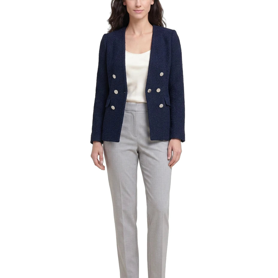 Woman wearing a navy blazer with white buttons, white top, and gray pants on a white background