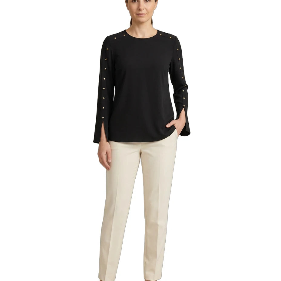Woman wearing a black top with studded details and beige pants on a white background