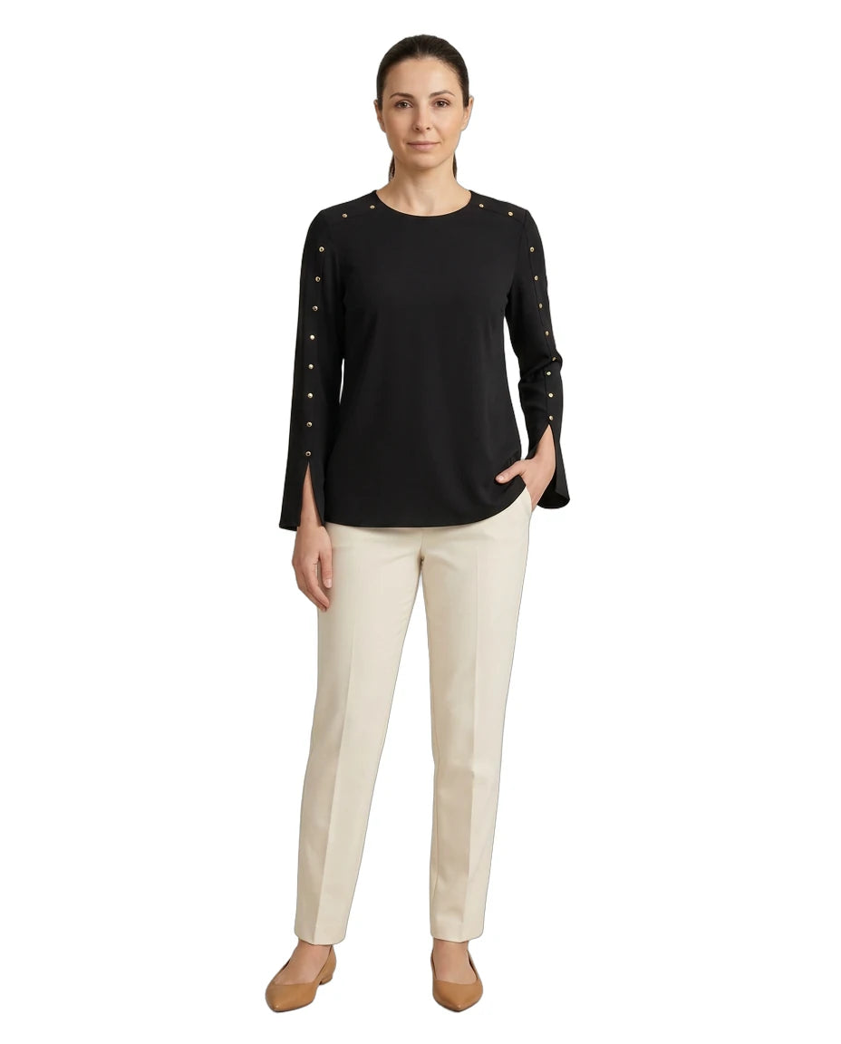 Woman wearing a black top with studded details and beige pants on a white background
