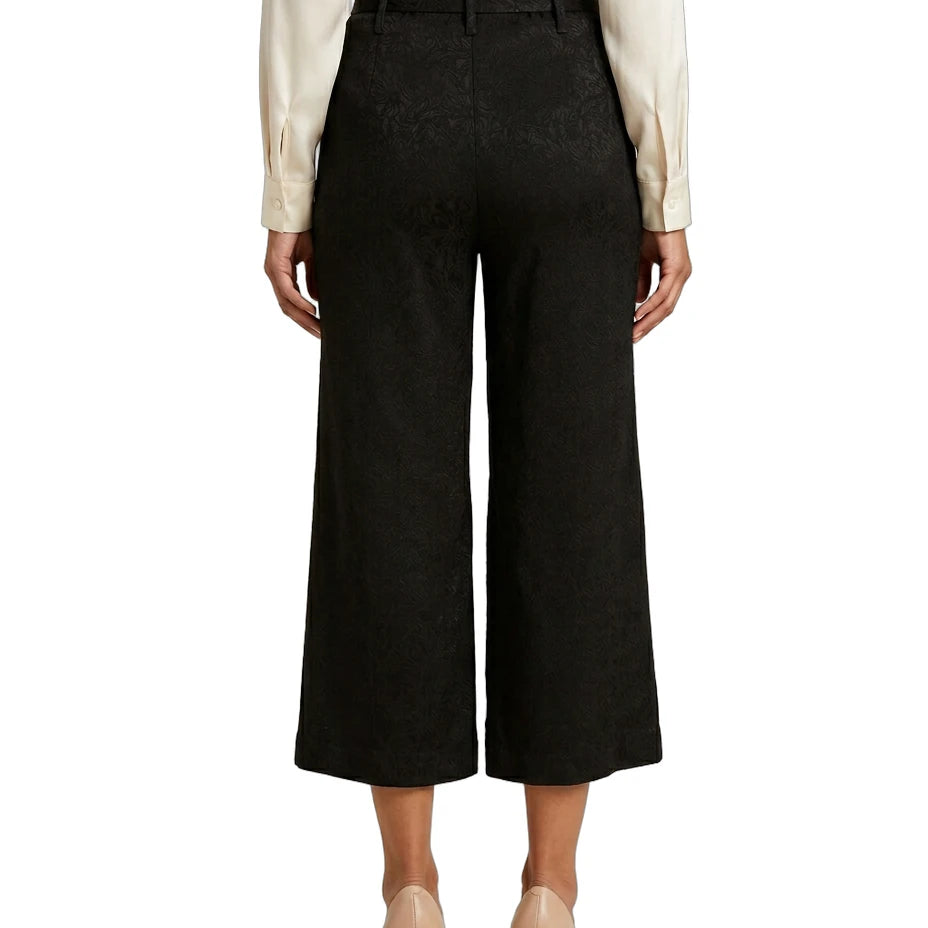 Person wearing black Calvin Klein wide-leg pants with a white shirt on a white background