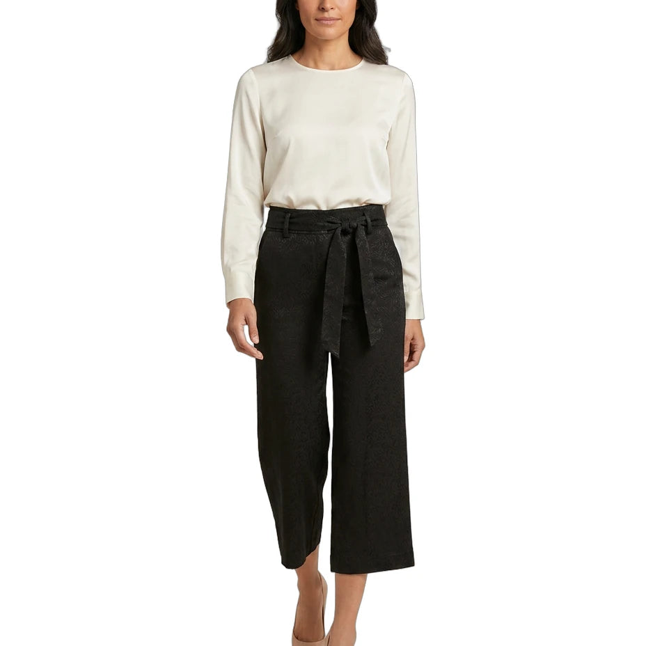 Woman wearing a white blouse and black Calvin Klein pants on a white background