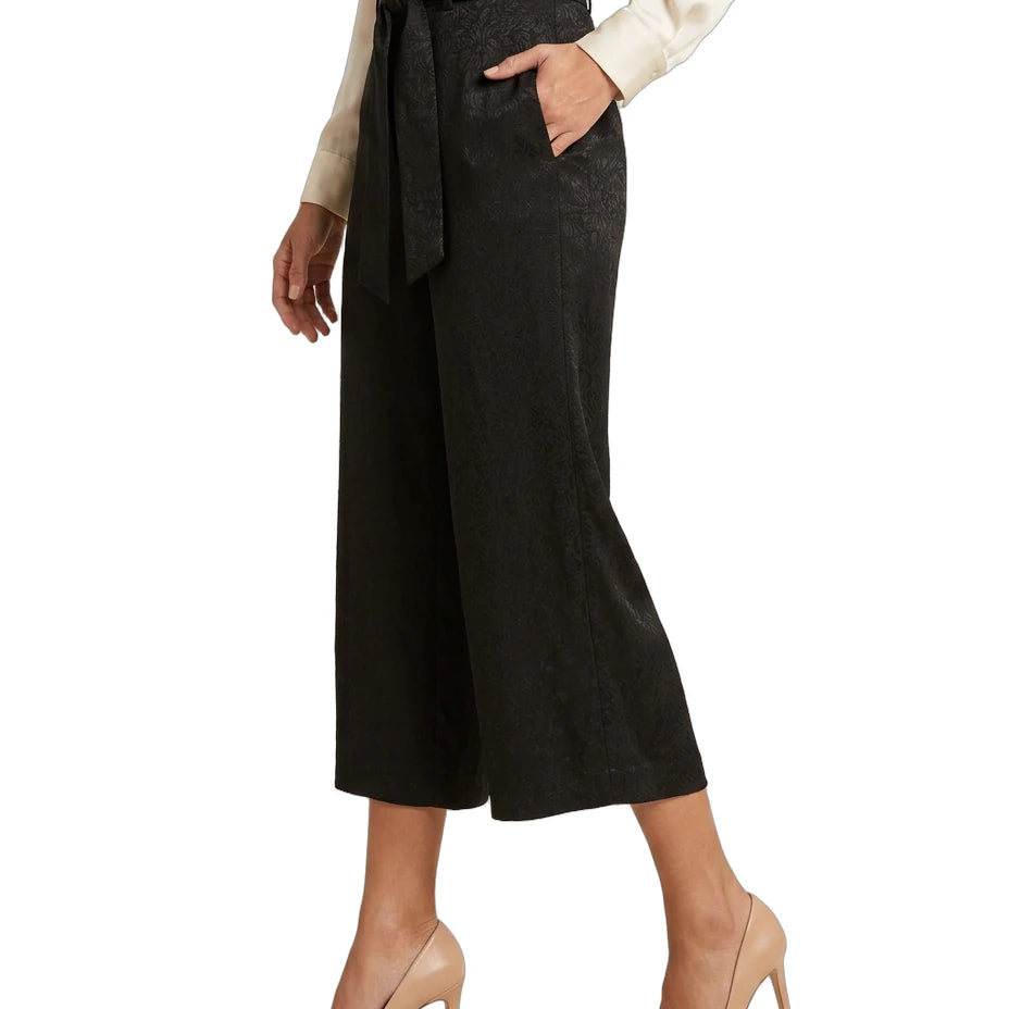Person wearing black Calvin Klein wide-leg pants with a belt on a white background
