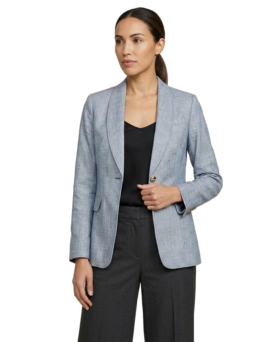 Woman wearing a light blue Calvin Klein blazer over a black top and pants on a white background