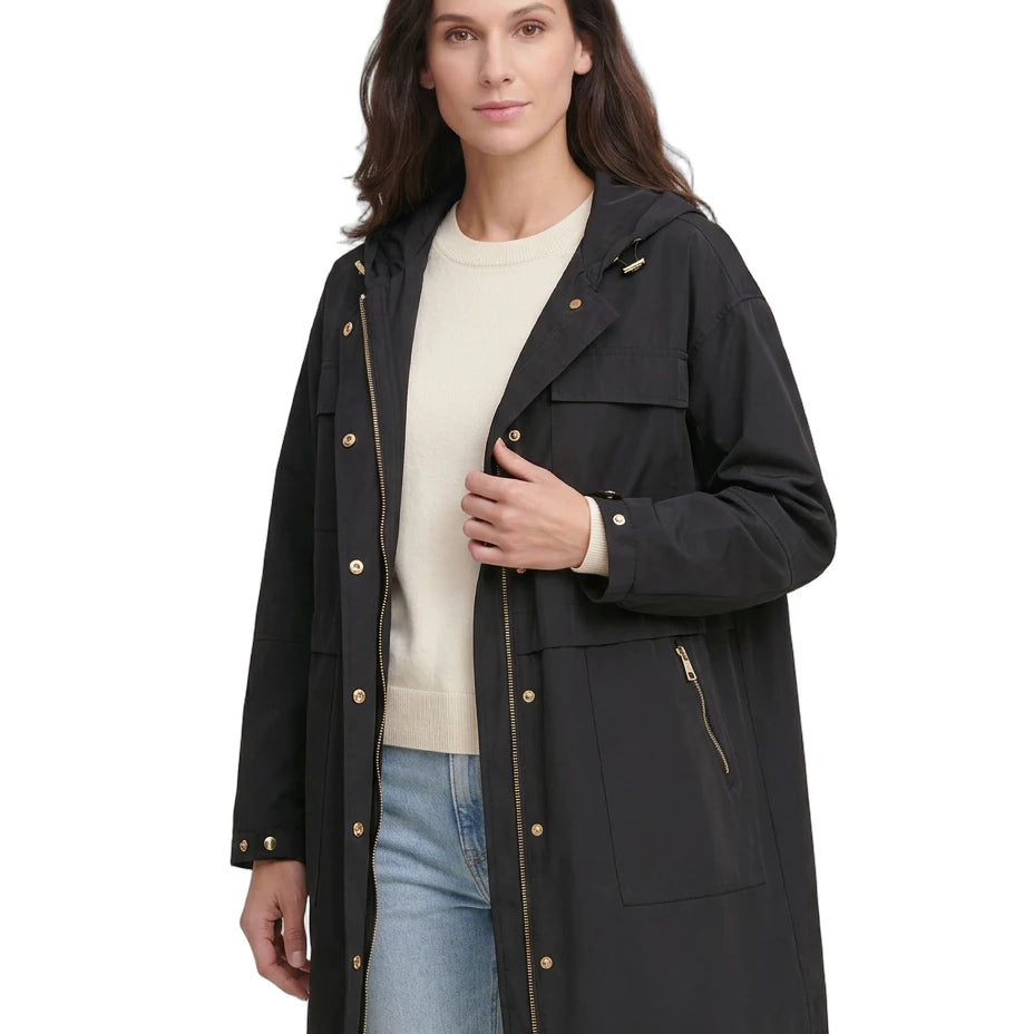 Woman wearing a black Calvin Klein coat with gold buttons on a white background