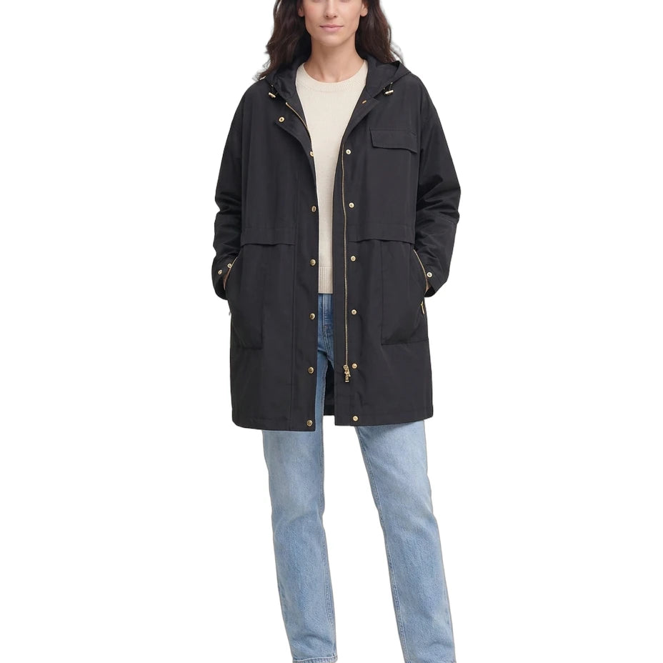 Woman wearing a black Calvin Klein coat, beige sweater, and blue jeans on a white background
