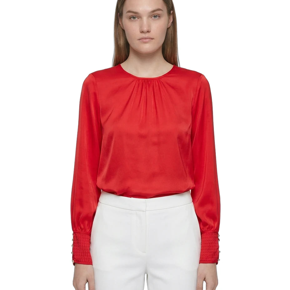 Person wearing a red blouse and white pants on a white background