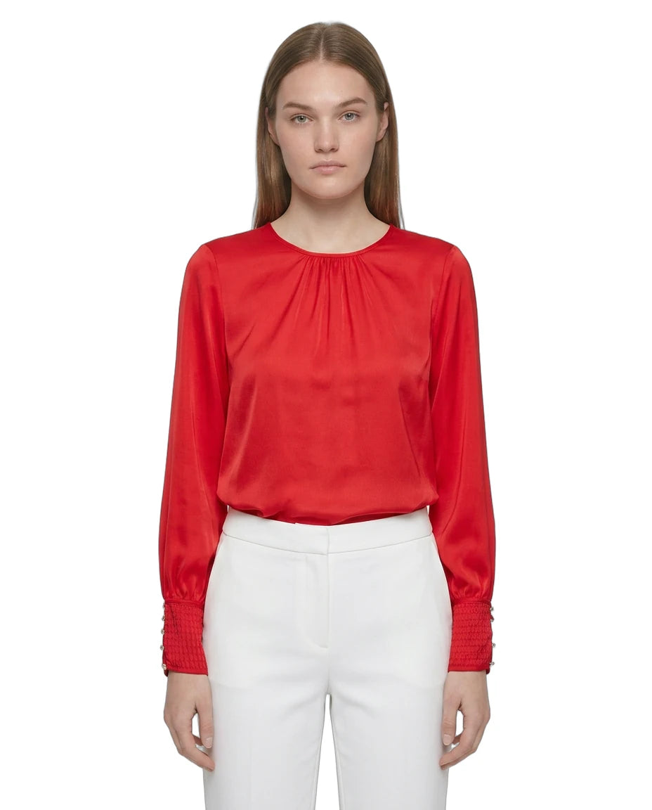Person wearing a red blouse and white pants on a white background