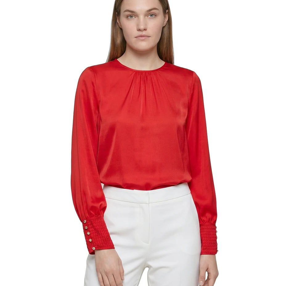 Woman wearing a red blouse with long sleeves and white pants on a white background