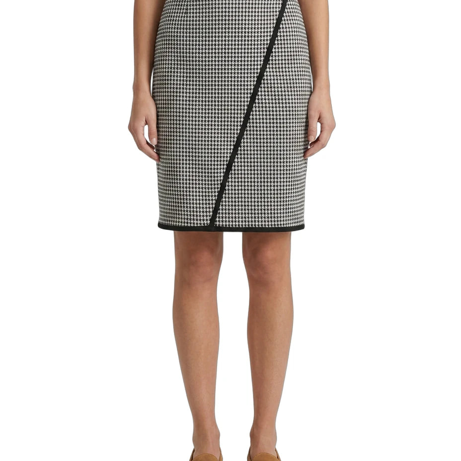 Person wearing a Calvin Klein black and white houndstooth patterned skirt with a plain background