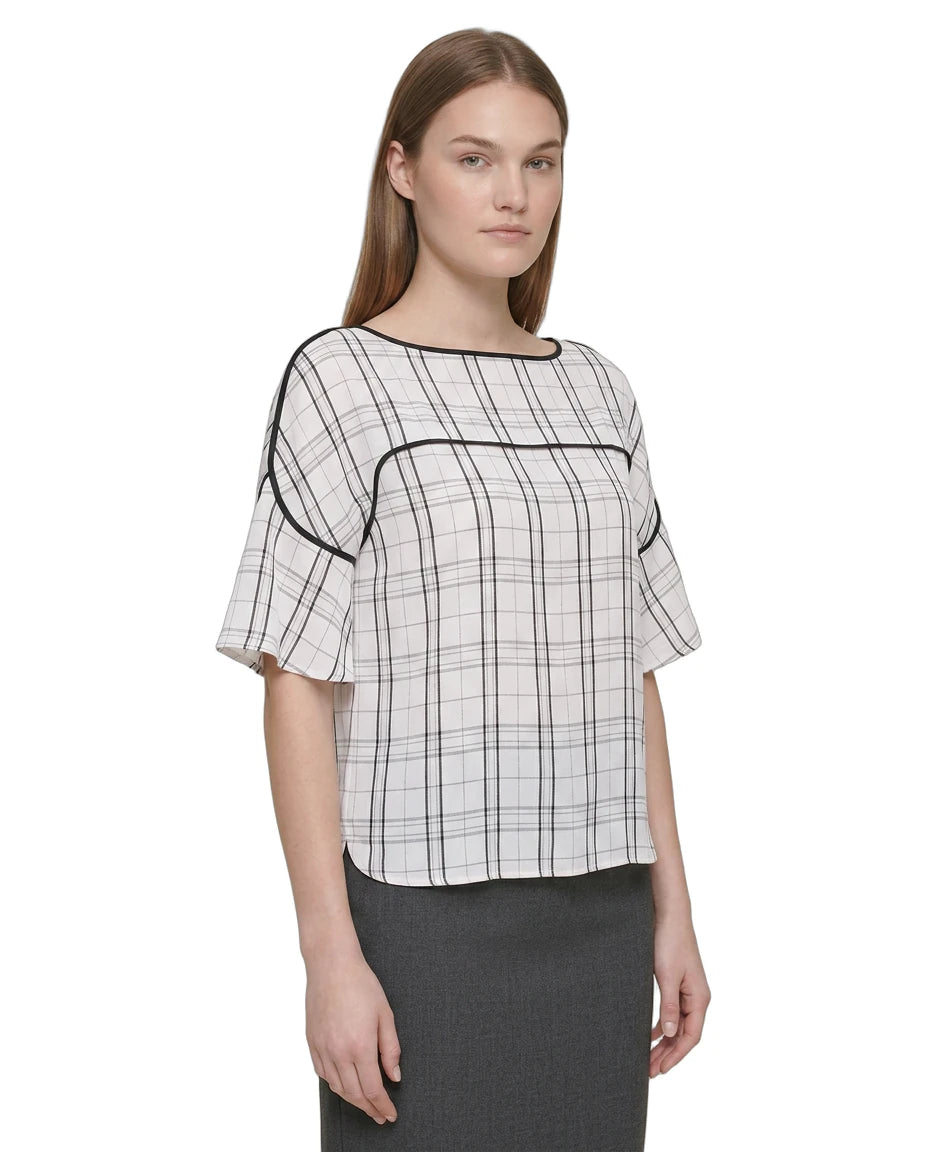 Woman wearing a Calvin Klein black and white checkered blouse with a plain background