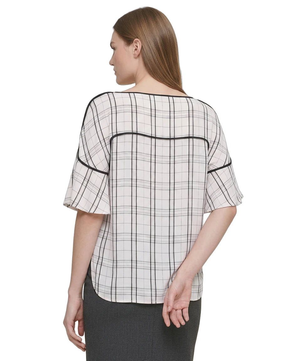 Woman wearing a Calvin Klein black and white checkered blouse with a plain background