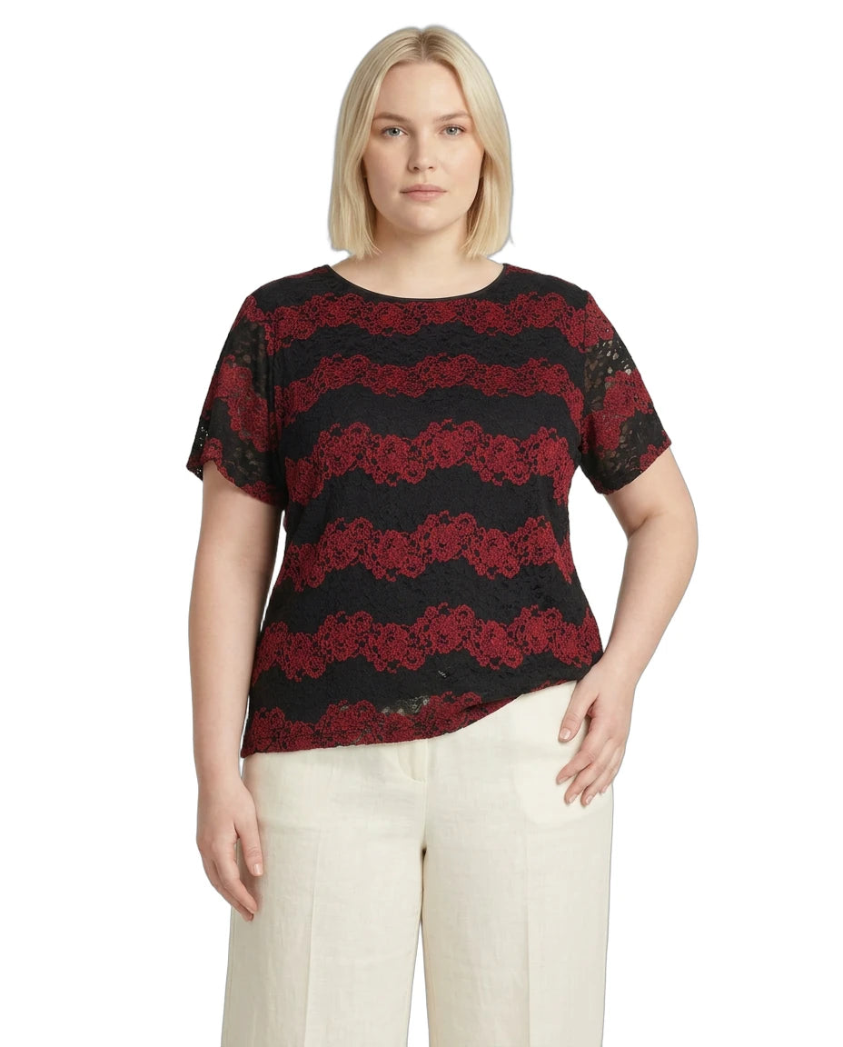 Woman wearing a black and red lace top with white pants on a white background