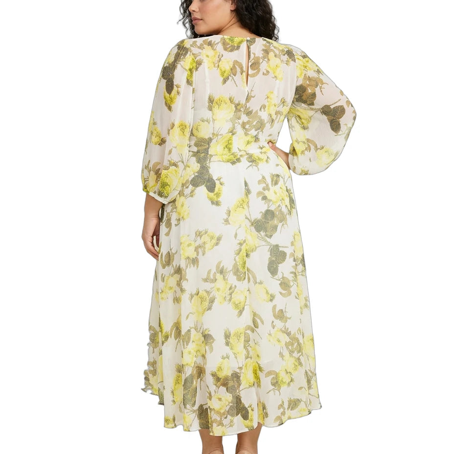 Woman wearing a Calvin Klein floral dress with sheer sleeves on a white background