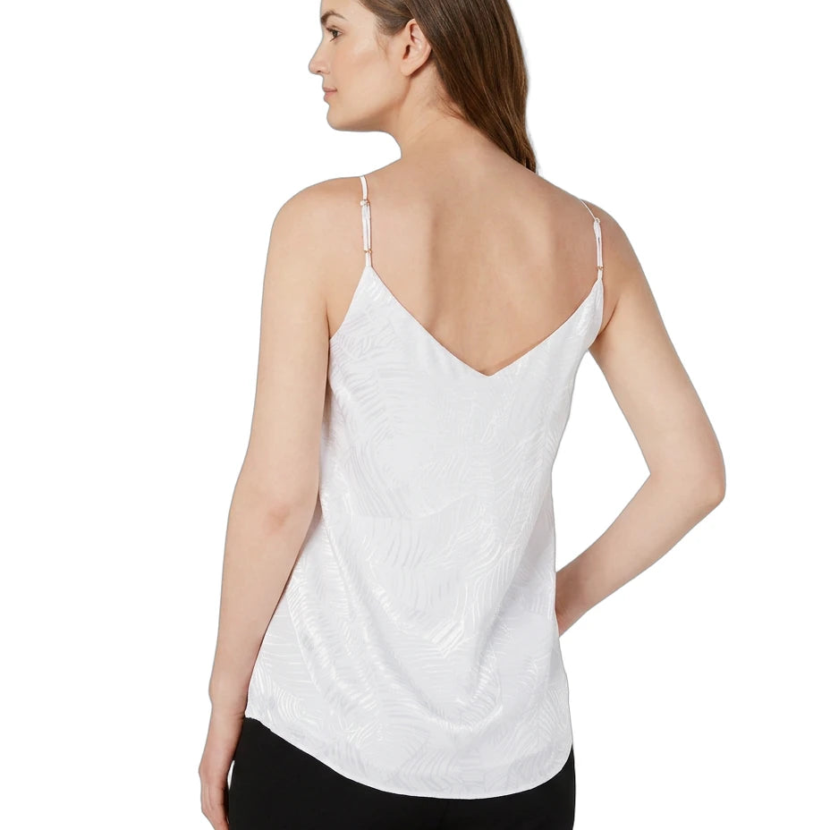 Woman wearing a white Calin Klein spaghetti strap top on a white background
