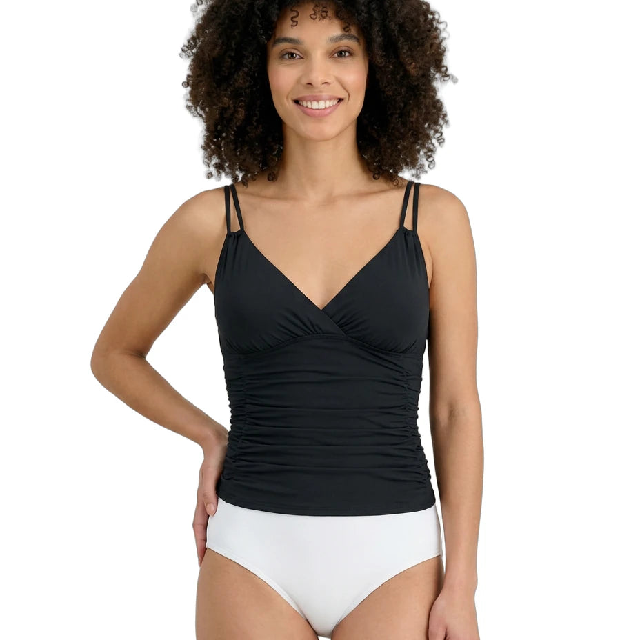 Woman wearing a black Calvin Klein tankini top and white bottoms on a white background