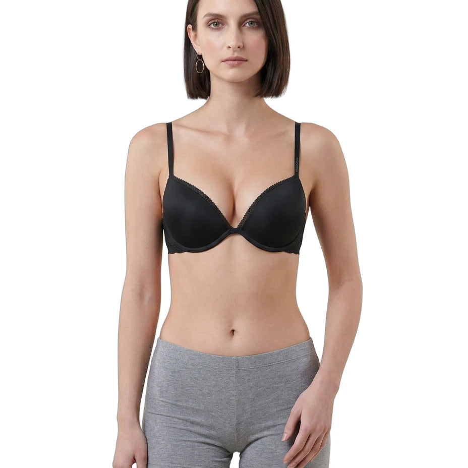 Woman wearing a black Calvin Klein bra and gray shorts on a white background