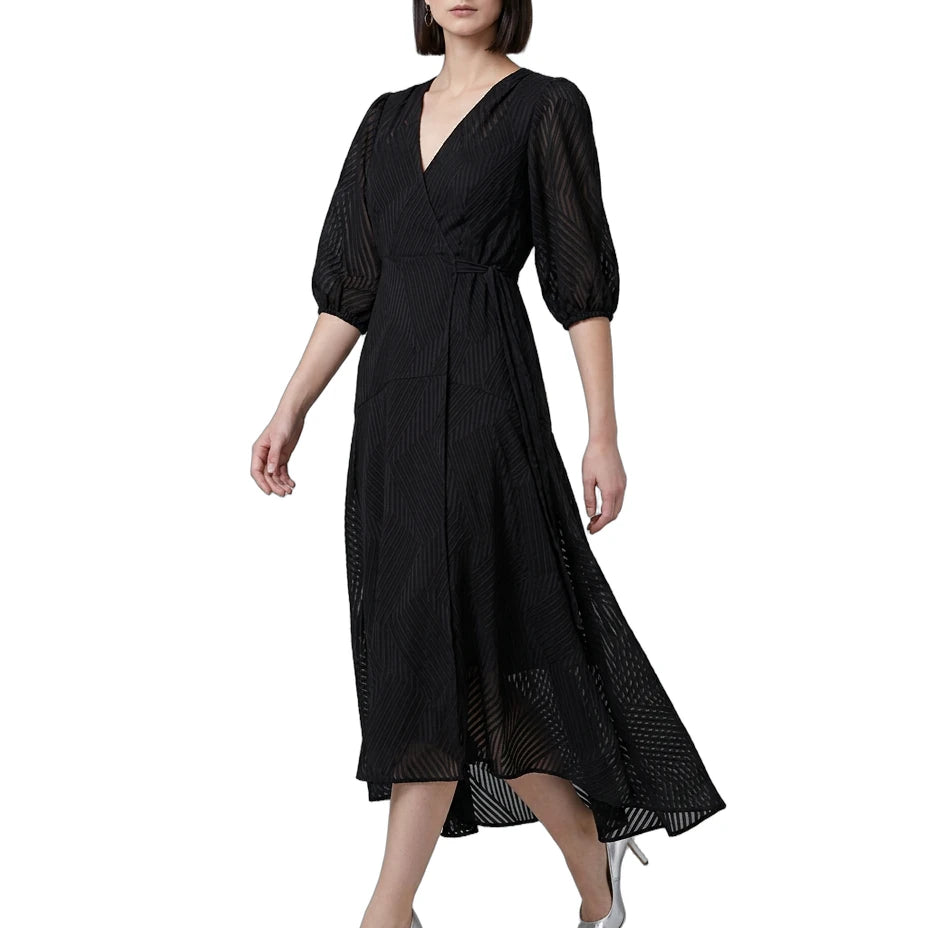 Woman wearing a black Calvin Klein dress with sheer sleeves on a white background