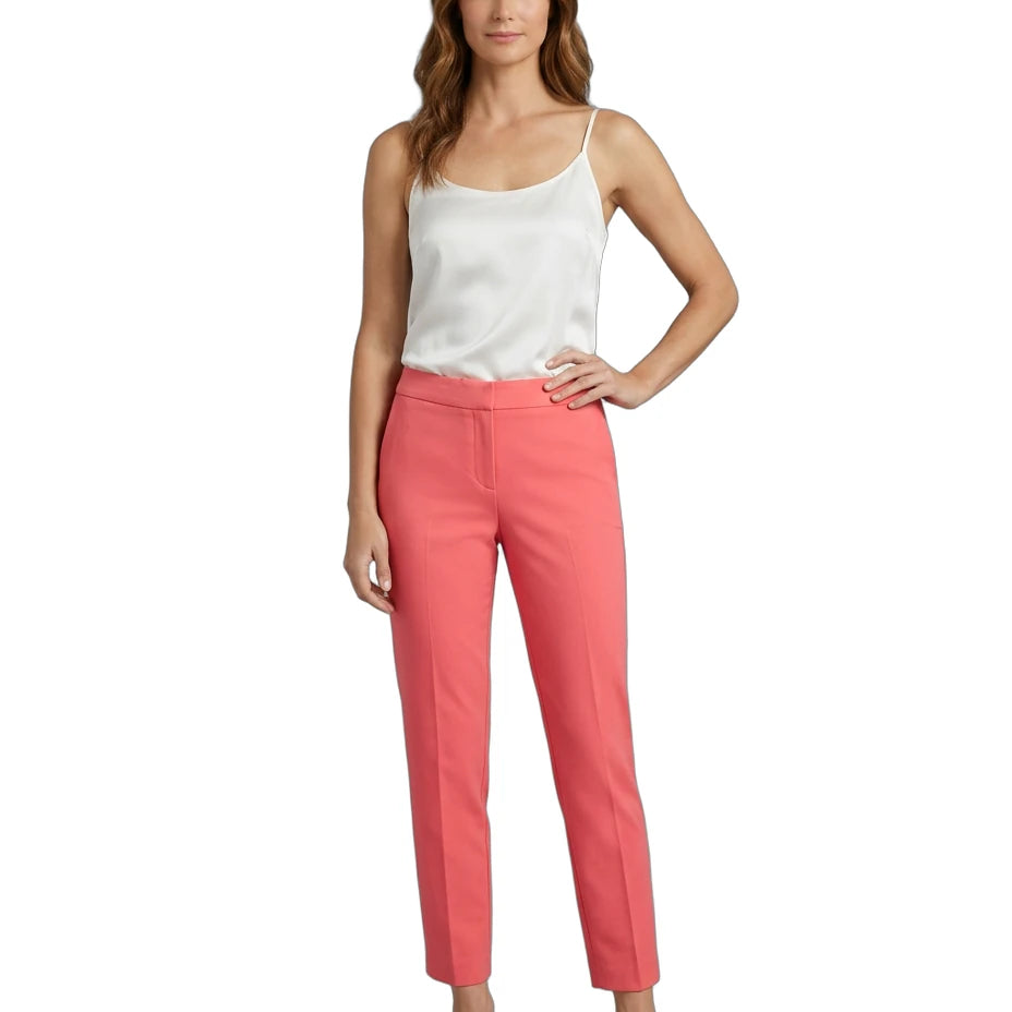 Woman wearing a white top and Calvin Klein coral pants on a white background