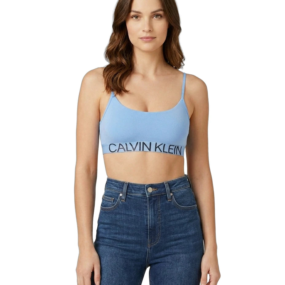 Woman wearing a Calvin Klein blue sports bra and jeans on a white background