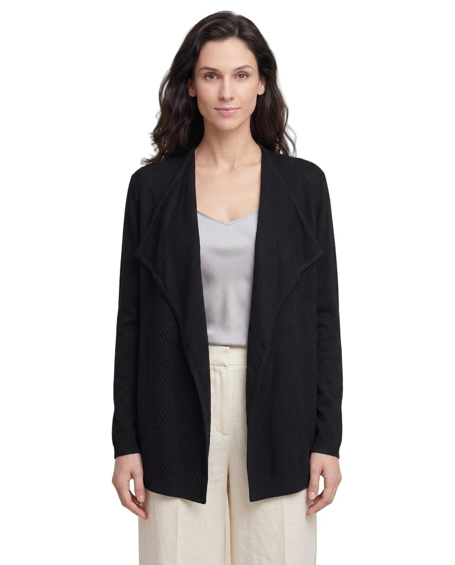 Woman wearing a black Calvin Klein cardigan over a light gray top and beige pants on a white background