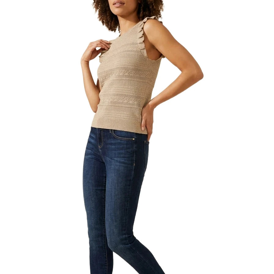 Full-length view of a woman wearing the INC International Concepts beige sleeveless ruffle-trim sweater, dark wash skinny jeans, and black heeled boots.