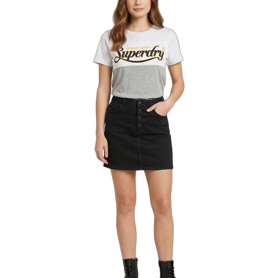 A woman modeling a light gray Superdry graphic t-shirt paired with a black denim mini skirt and black combat boots, set against a plain white background.