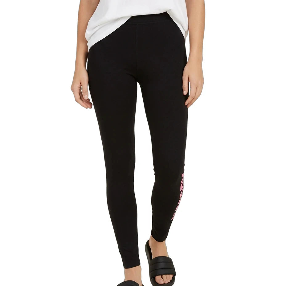 A model wearing black leggings with a pink and white graphic print on the side, styled with a white t-shirt and black slide sandals against a plain white background.