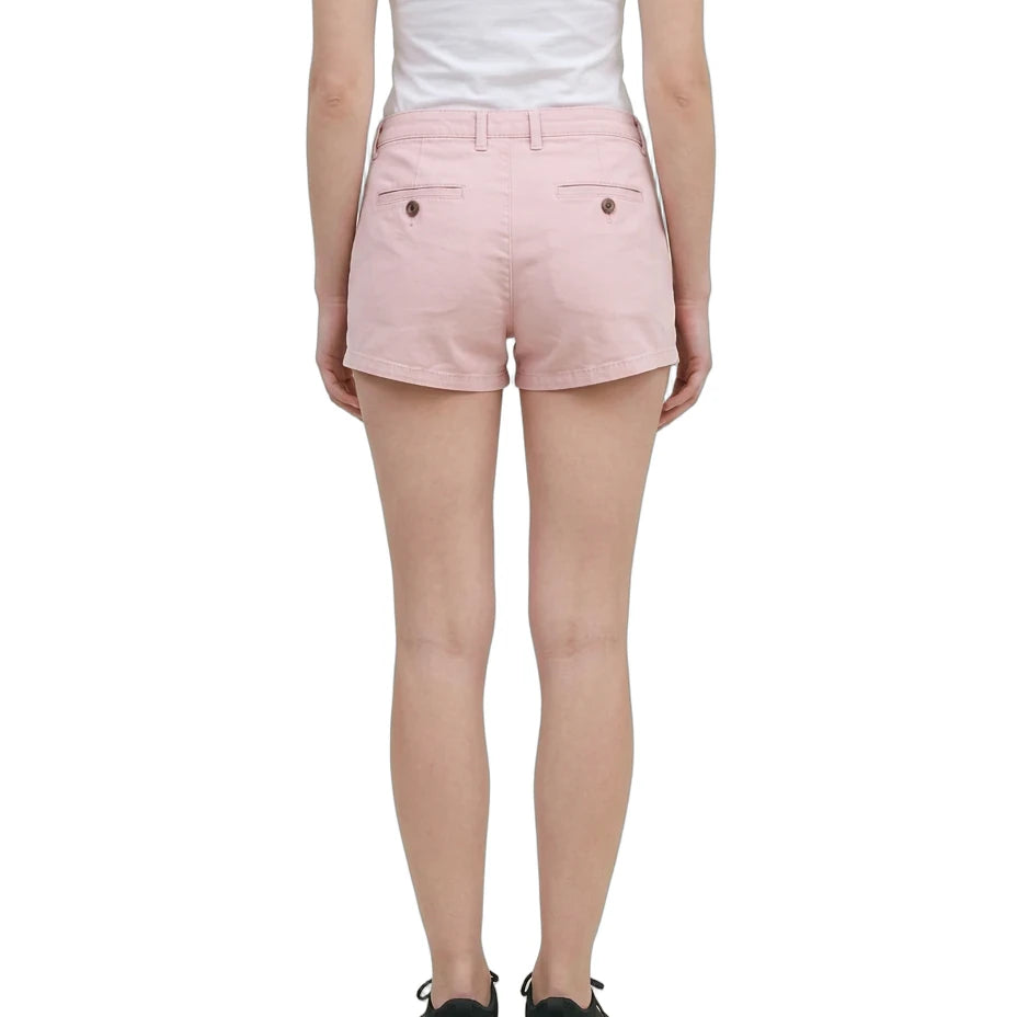 A model wearing light pink chino shorts, a white tank top, and black sneakers, shown from the waist down against a plain white background.